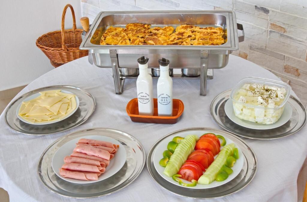 Ein reichhaltiges Buffet mit verschiedenen Speisen, darunter Käse, Schinken, Gemüse und eine Auflaufform.