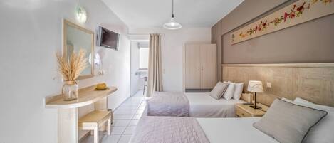 A hotel room with two beds, a desk with a mirror, a TV, and a decorative wall.