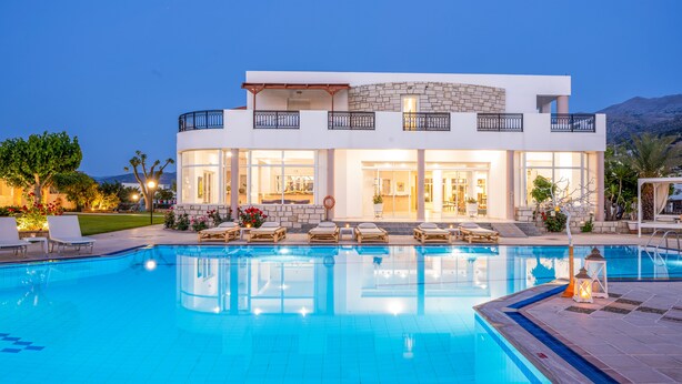 A modern two-story house with a swimming pool, outdoor seating, and a well-lit entrance. - Maria Rousse (Hersonissos)