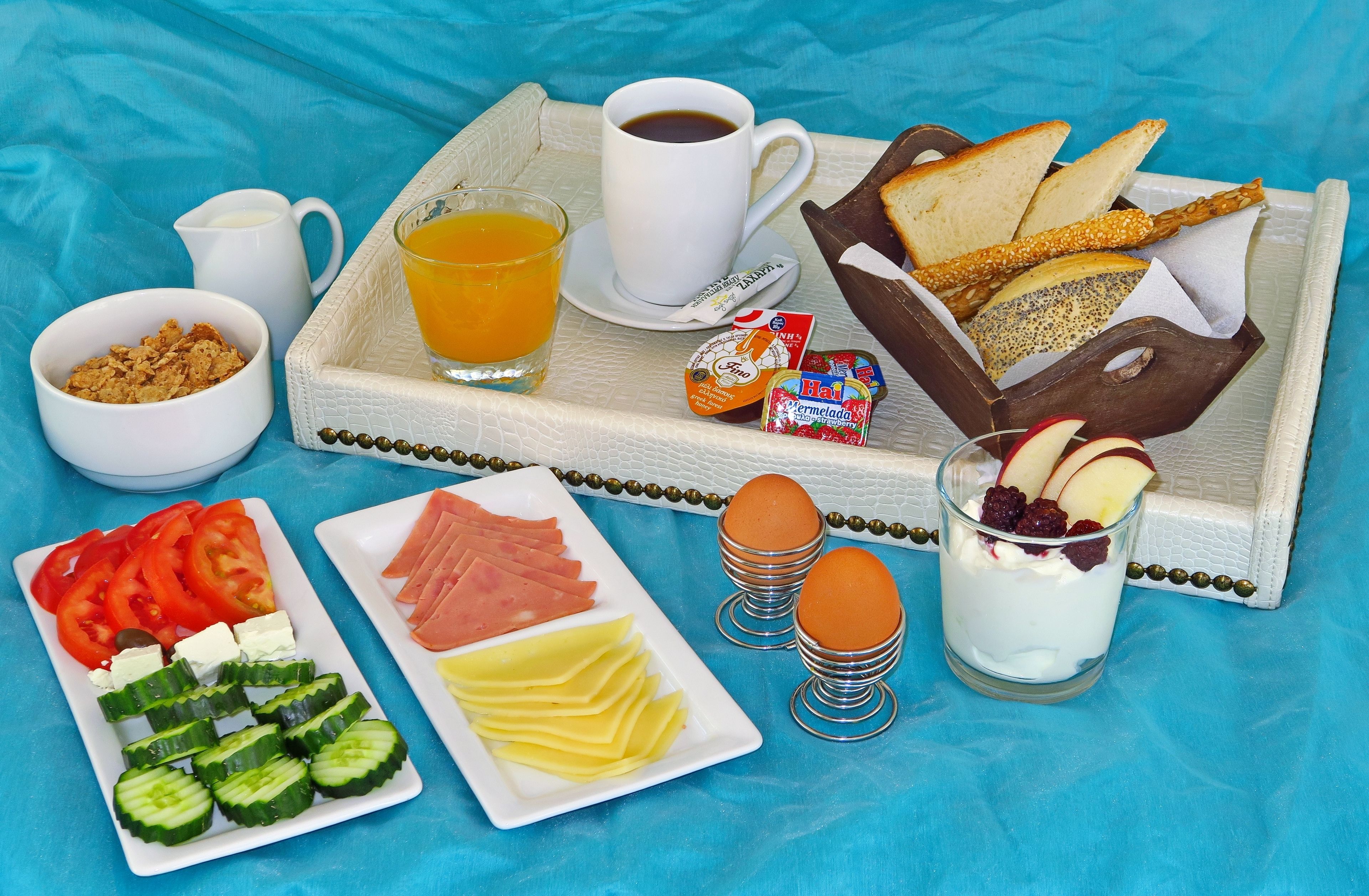 A breakfast tray with various food items including bread, cheese, ham, eggs, and fruit.