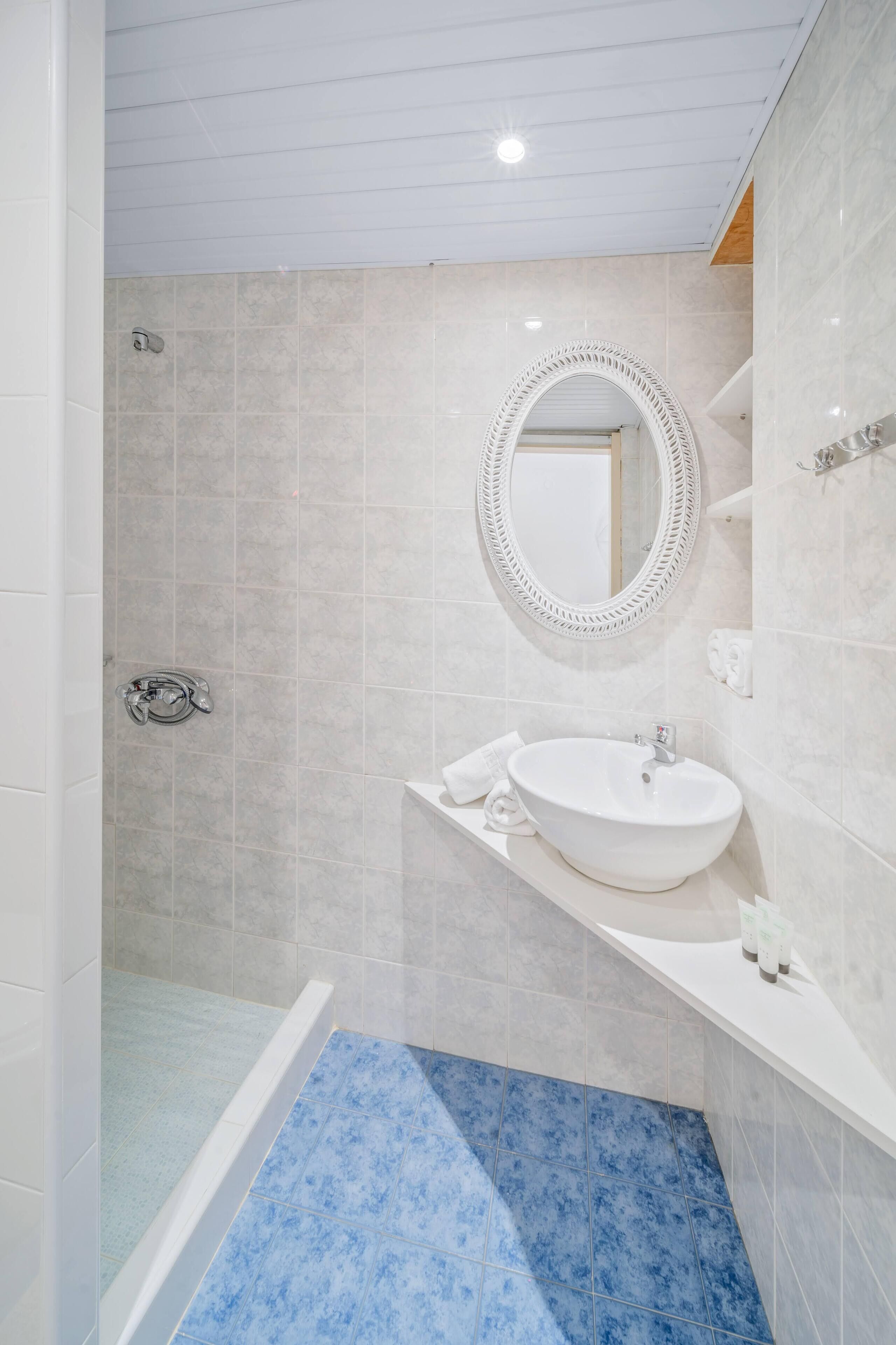 Un baño moderno con ducha, lavamanos y espejo.