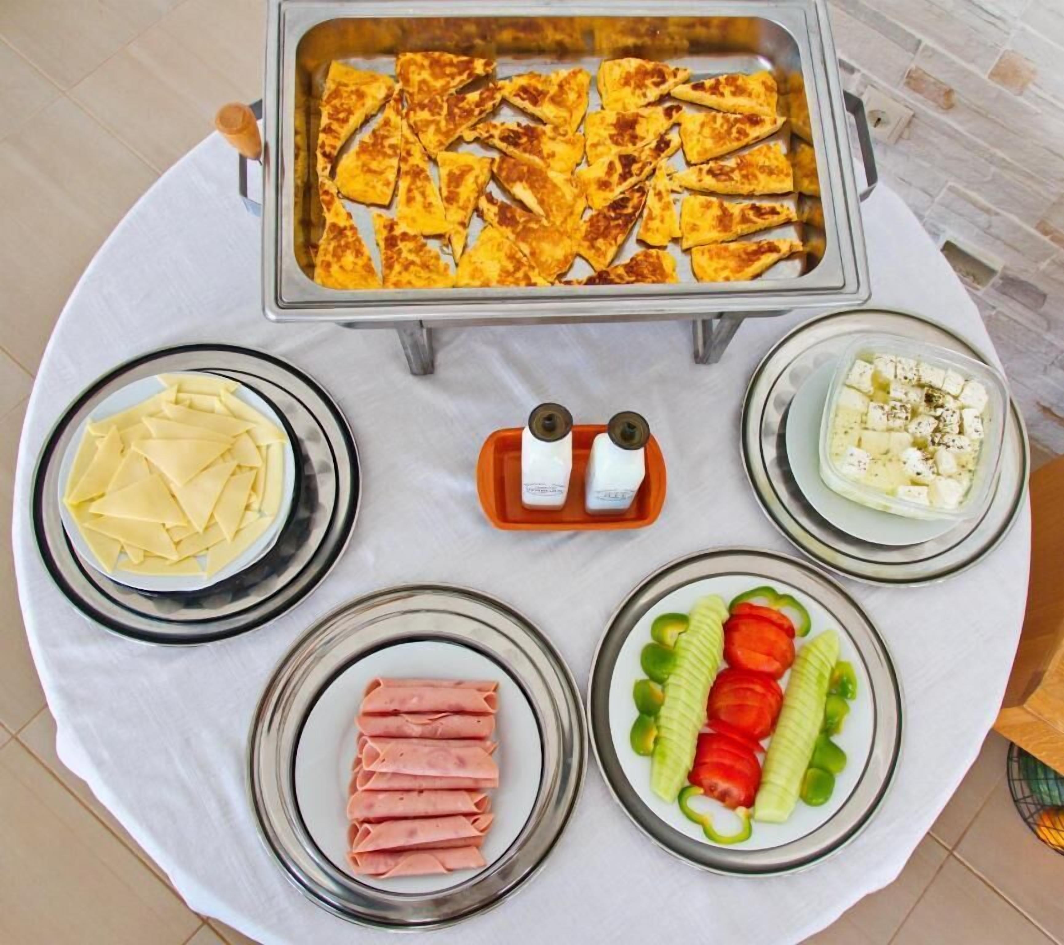 A buffet table with various food items including cheese, ham, vegetables, and a tray of baked items.