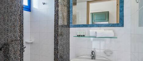 A bathroom with a white sink, a mirror, and a shower area.