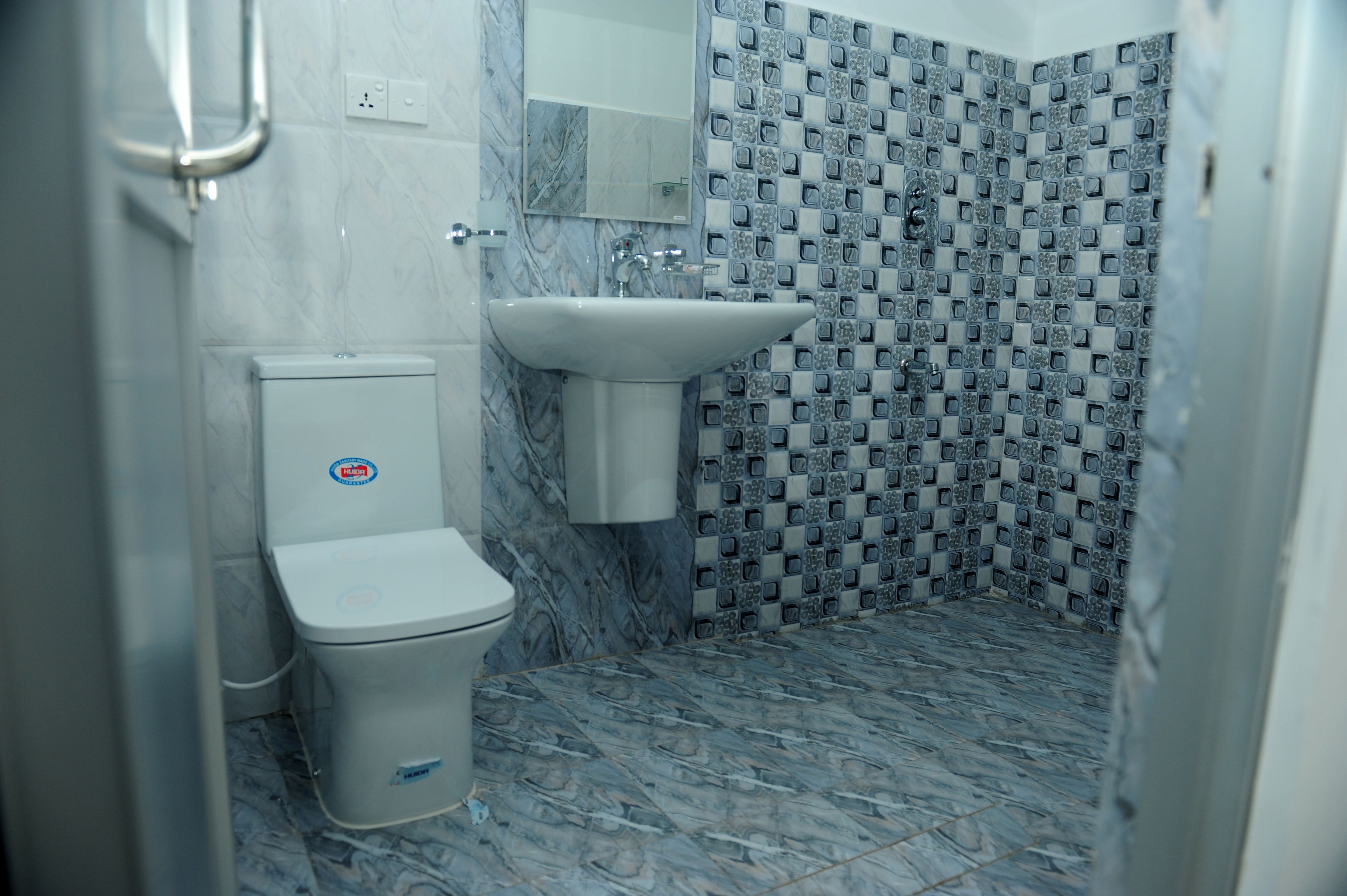 A bathroom with a toilet, sink, and tiled shower area.