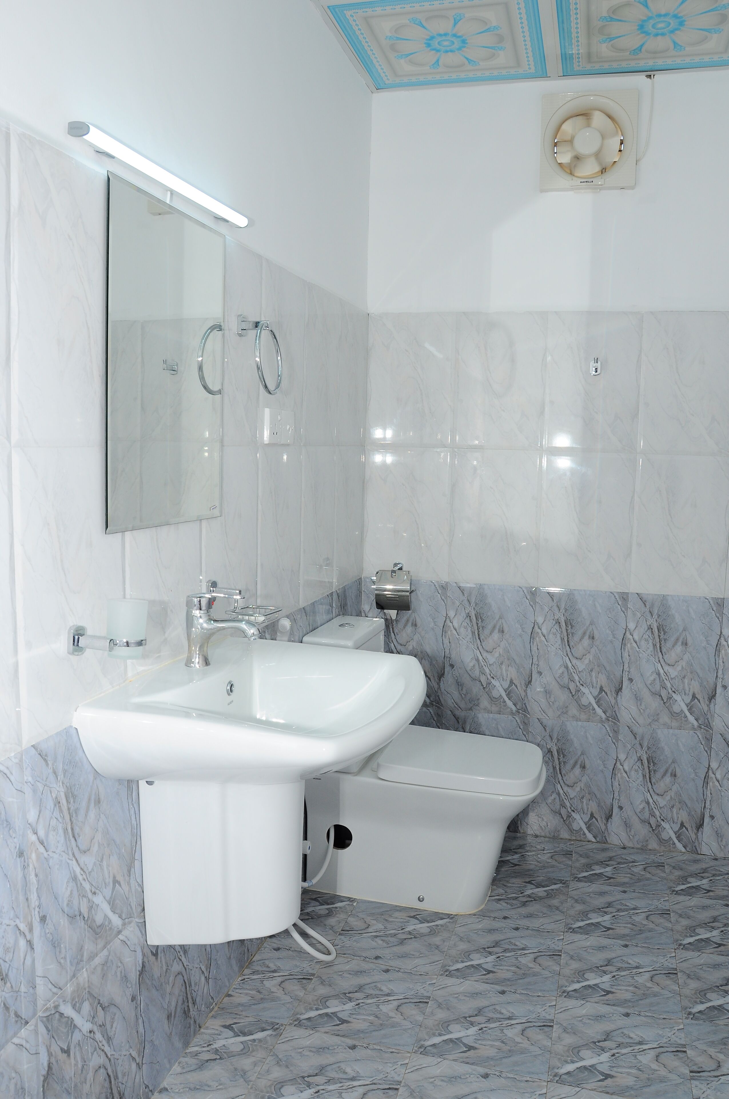 A bathroom with a white sink, a toilet, and a mirror.