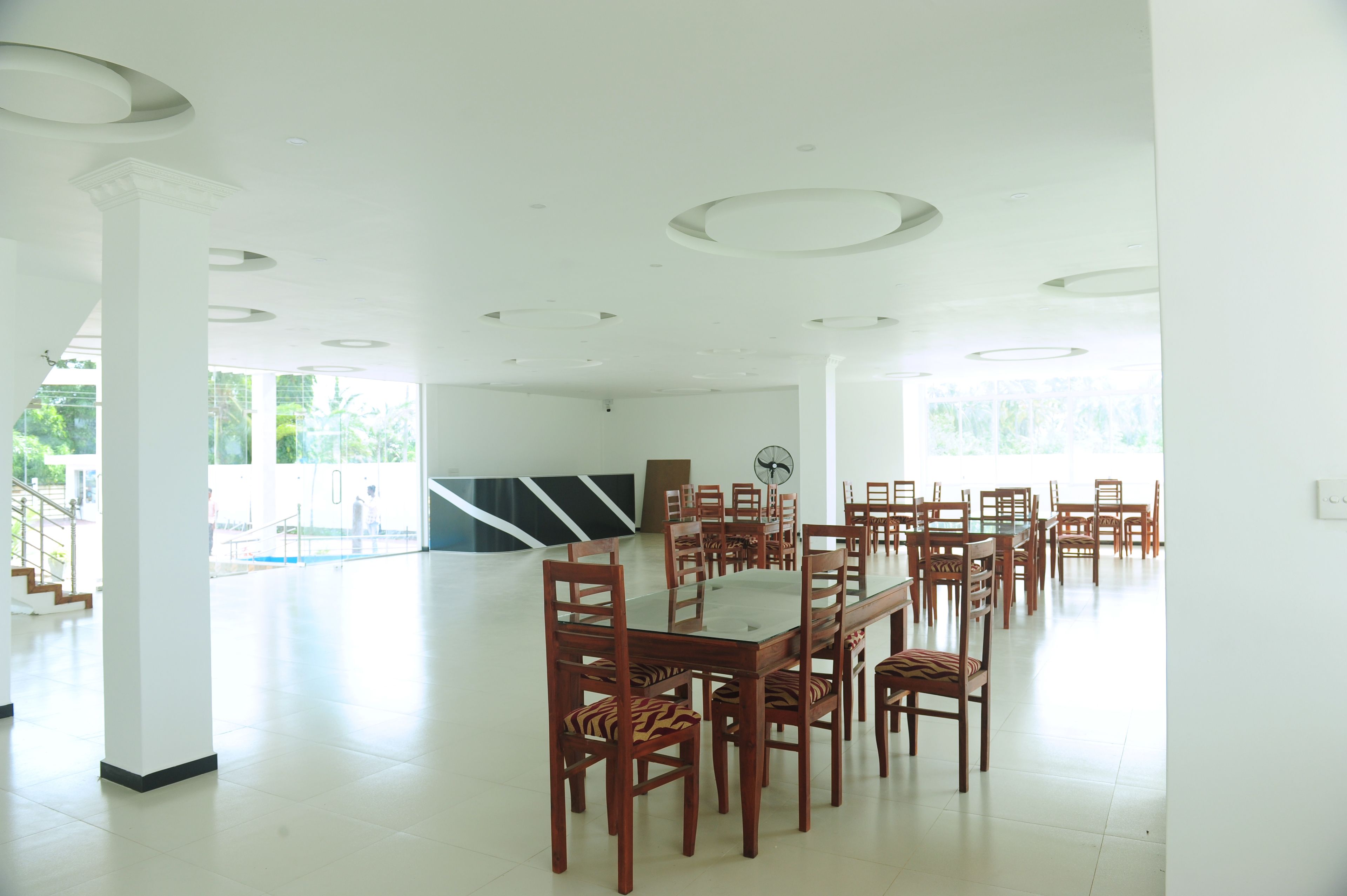 A spacious, well-lit conference room with a large table and multiple chairs, white walls, and a ceiling with circular light fixtures.