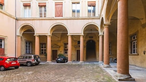 A courtyard with a brick floor, columns, and arches.