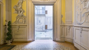 A hallway with ornate wall decorations, a statue, and a view of the outside.