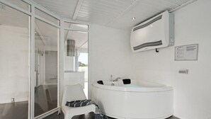 Ein modernes Badezimmer mit einer weißen Badewanne, einer Duschkabine aus Glas und einem weißen Stuhl mit einem Handtuch.