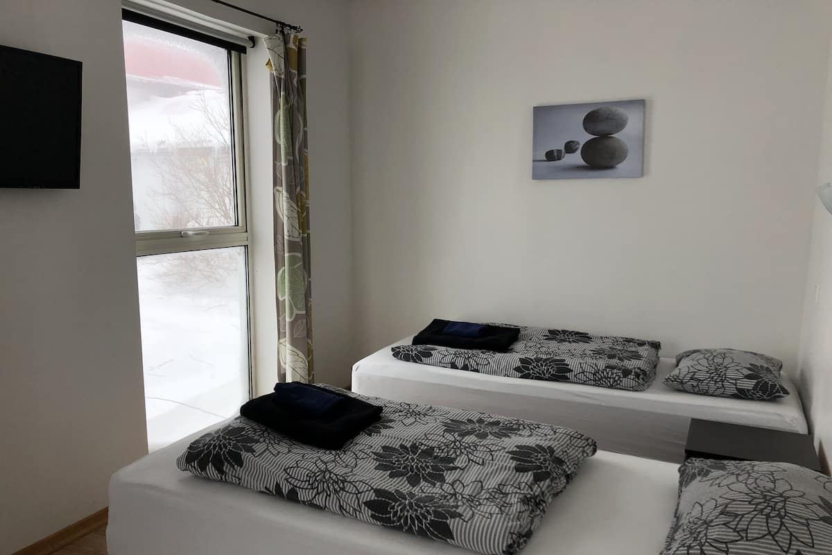 A room with a bed, a window with a view of a snowy landscape, and a framed picture on the wall.