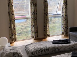 Una habitación con un ventanal grande, suelo de madera y una cama con ropa de cama a rayas.