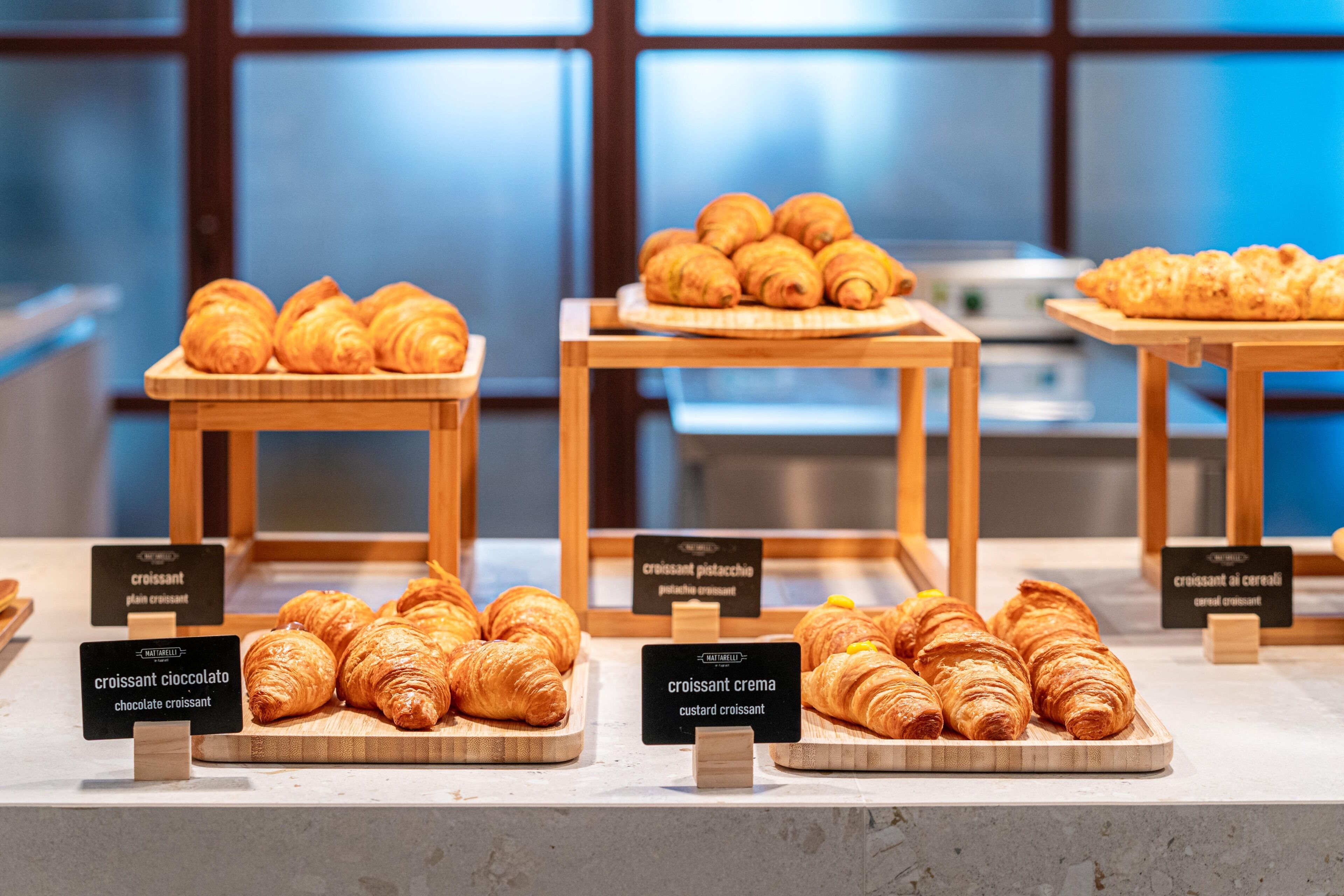 Una vetrina di pasticceria con diversi tipi di croissant, tra cui cioccolato e crema pasticcera.