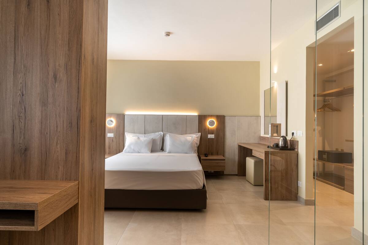 A modern bedroom with a large bed, bedside tables, a nightstand, and a built-in wardrobe.