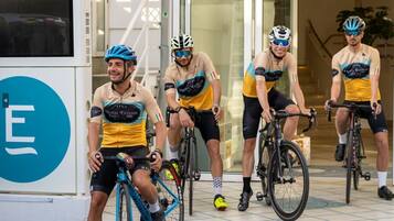 A group of cyclists in cycling attire near a building entrance.