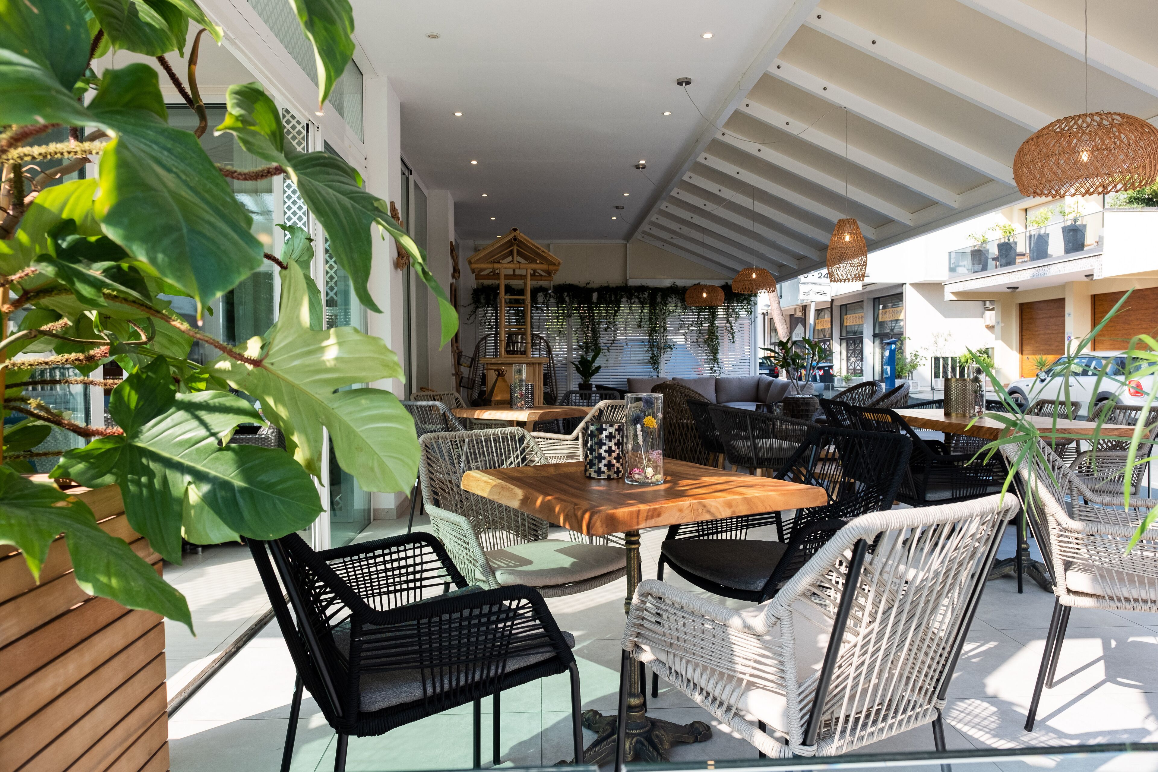 Un espace extérieur moderne, aménagé avec des meubles en osier, une table en bois et une structure décorative en bois.