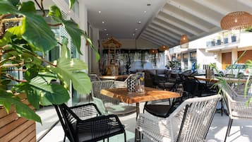 Un espace extérieur moderne, aménagé avec des meubles en osier, une table en bois et une structure décorative en bois.