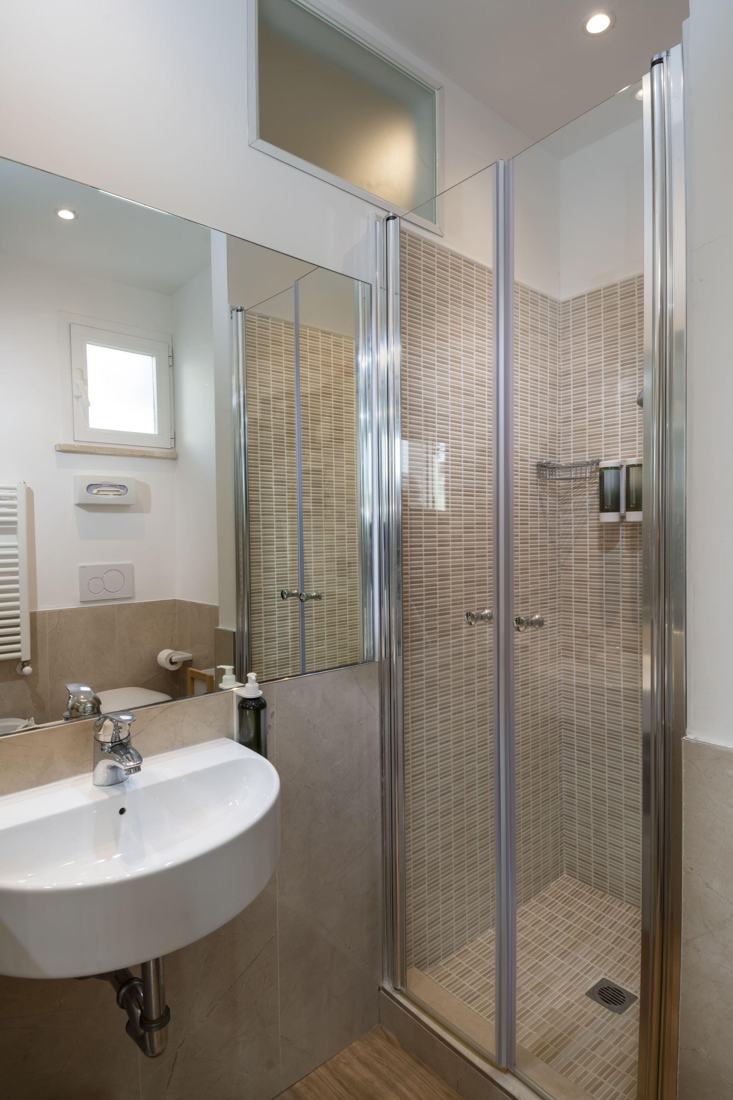 Een moderne badkamer met een douchecabine van glas, een witte wastafel en een spiegel.