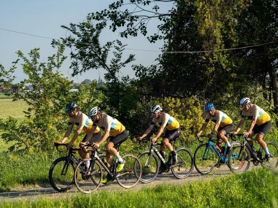 Een groep fietsers op een landelijke weg, omringd door groen.
