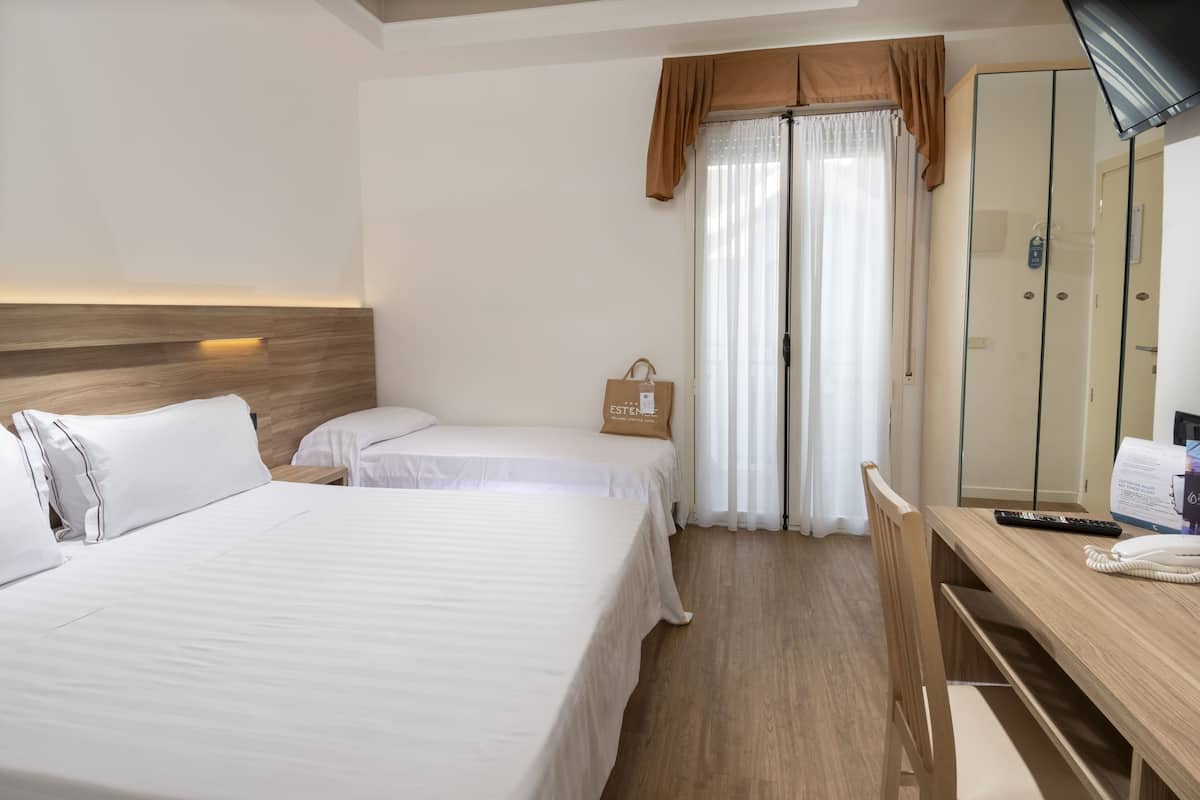 A hotel room with two beds, a wooden headboard, a desk with a telephone, and a mirror.