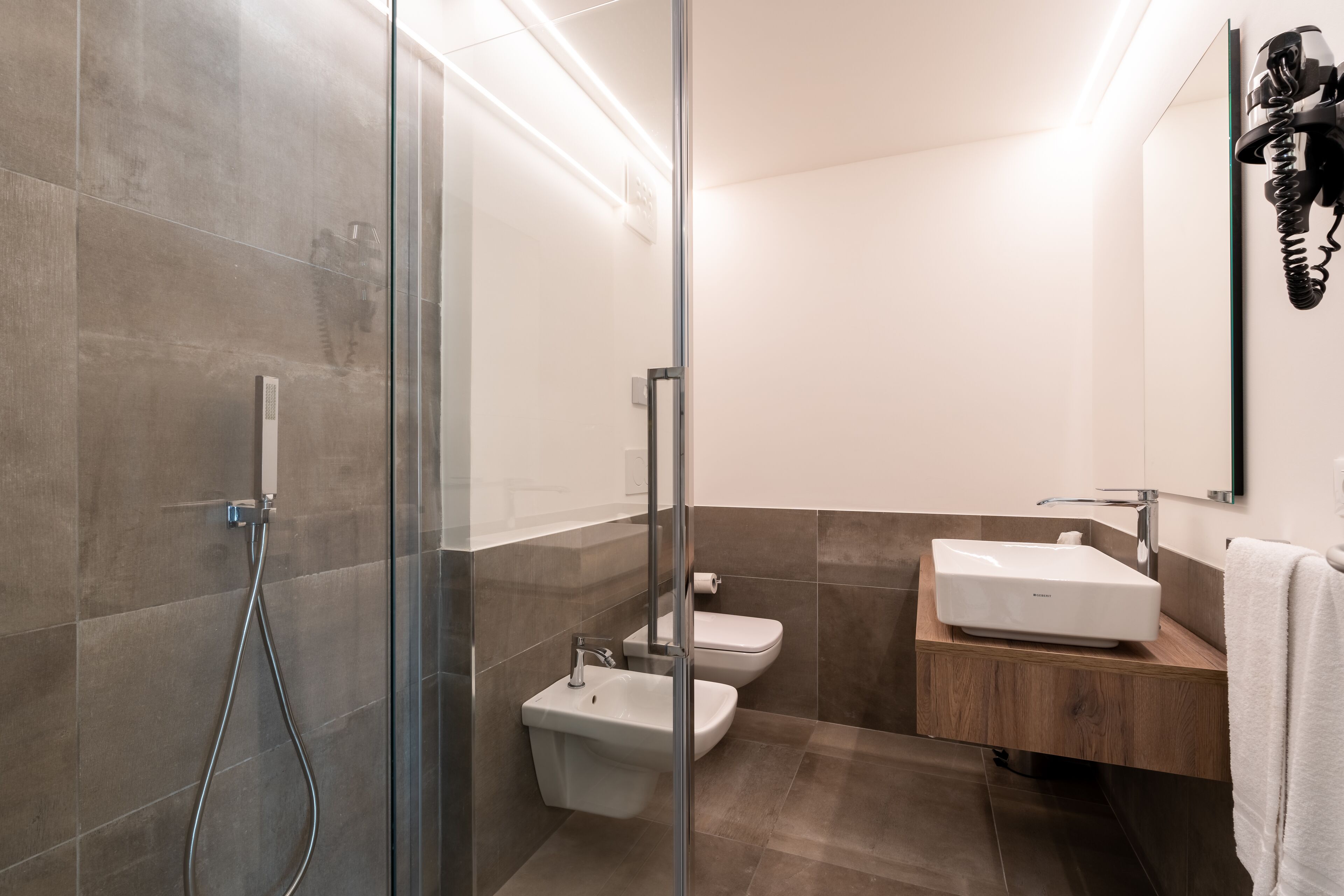 Une salle de bain moderne avec une douche à parois de verre, un lavabo blanc et des toilettes.