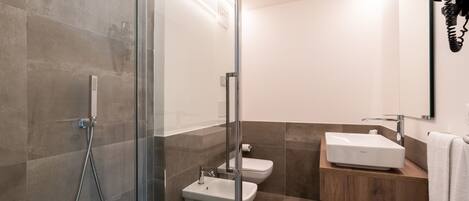A modern bathroom with a glass shower enclosure, a white sink, and a toilet.