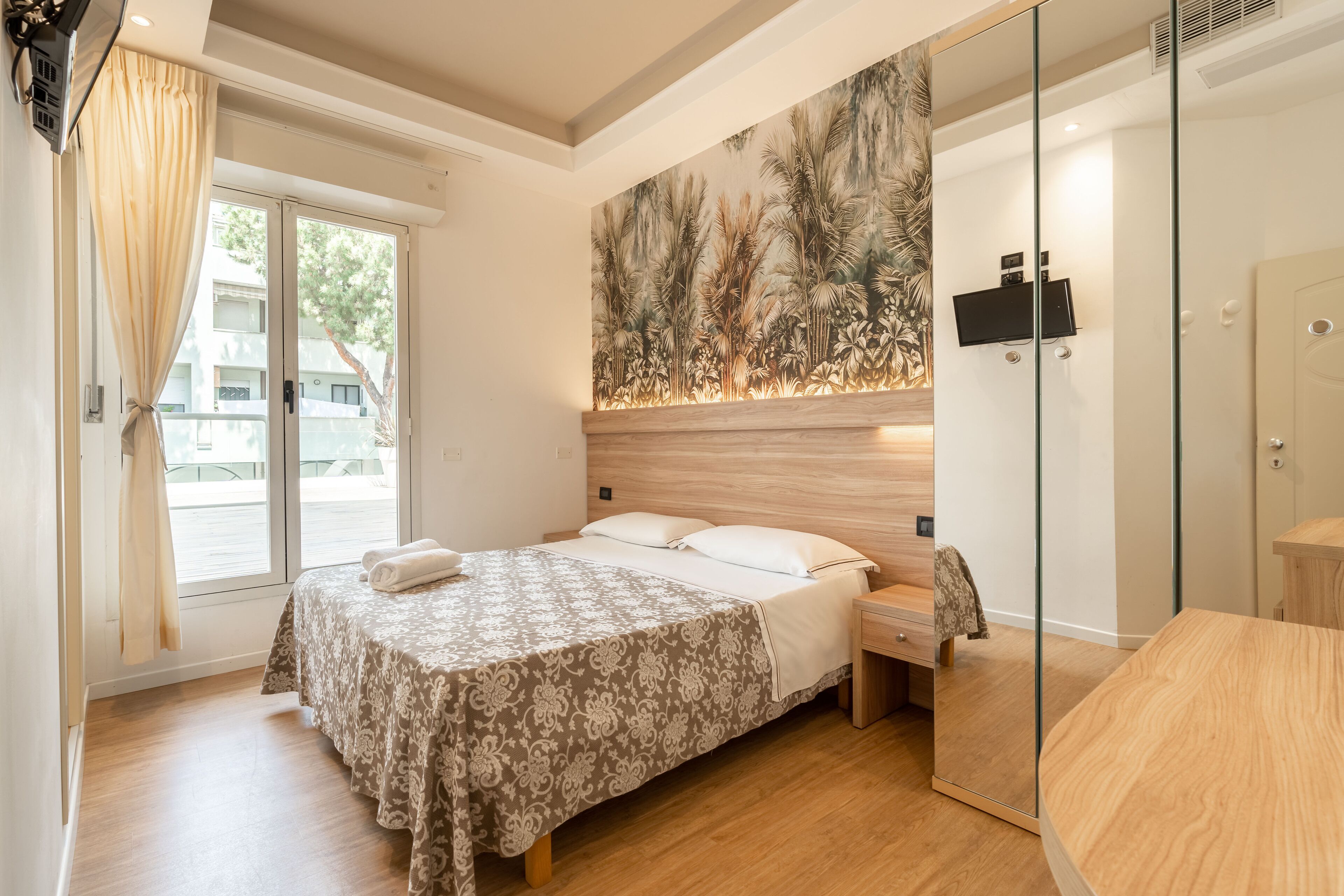 Un dormitorio con cama, mesita de noche y un espejo grande.