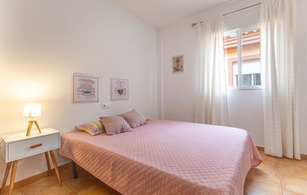 A bedroom with a bed, a bedside table, and a lamp. There are two wall decorations and a window with curtains. - Beautiful home in Cartagena (Cartagena)