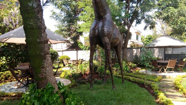 A garden with a tree sculpture, outdoor seating, and a pathway. - Twiga Sanctuary Resort (Kisumu)