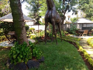 A garden with a tree sculpture, outdoor seating, and a pathway. - Twiga Sanctuary Resort (Kisumu)