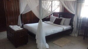 A bedroom with a four-poster bed, a wooden nightstand, and a white canopy. - Twiga Sanctuary Resort (Kisumu)