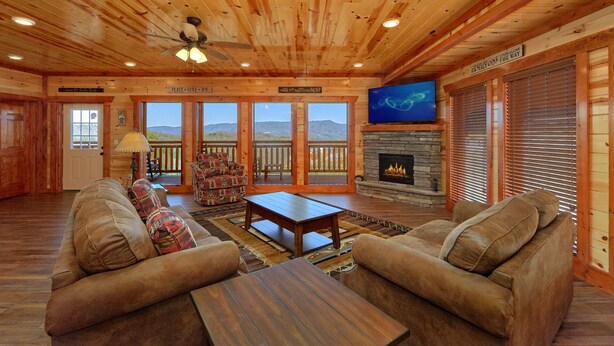 A cozy cabin interior with a fireplace, comfortable seating, and a large TV screen.