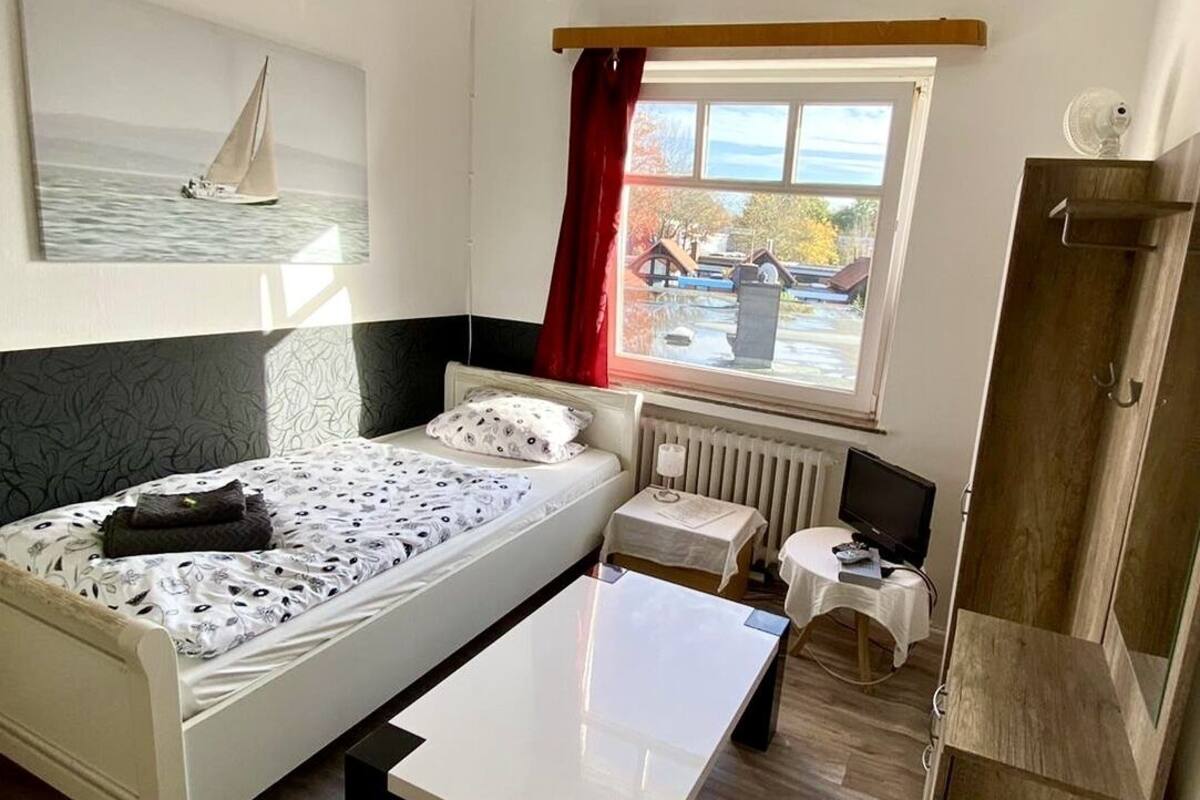 Une chambre à coucher avec un lit, une petite table, un téléviseur et une fenêtre donnant sur l’extérieur.