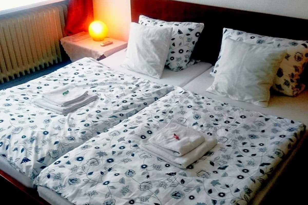 Une chambre d’hôtel avec un lit, des oreillers, une table de chevet, une lampe et un mur décoré de tableaux.