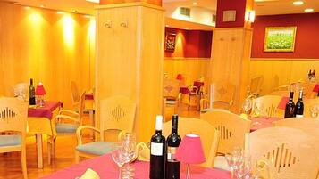 Un restaurante con varias mesas, sillas y botellas de vino.