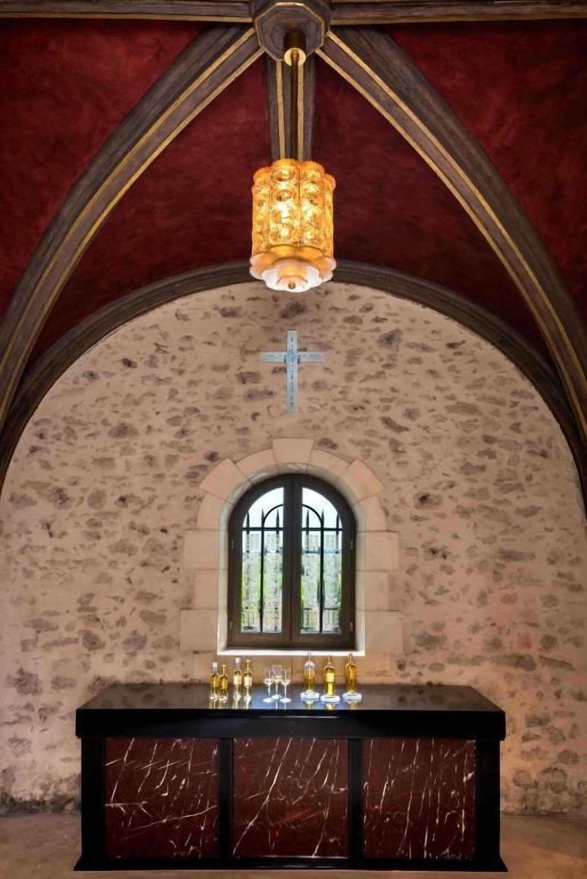A chapel interior with a marble altar, a cross, and a stained glass window.
