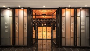 A modern hotel lobby with a polished black floor, a central wooden ceiling, and a wine rack in the background. - Château Lafaurie-Peyraguey Hôtel & Restaurant LALIQUE (Bommes)