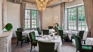 A dining area with green upholstered chairs, white tablecloths, and a chandelier. - Château Lafaurie-Peyraguey Hôtel & Restaurant LALIQUE (Bommes)