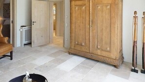 A spacious room with a large wooden cabinet, a radiator, and a door leading to another room.