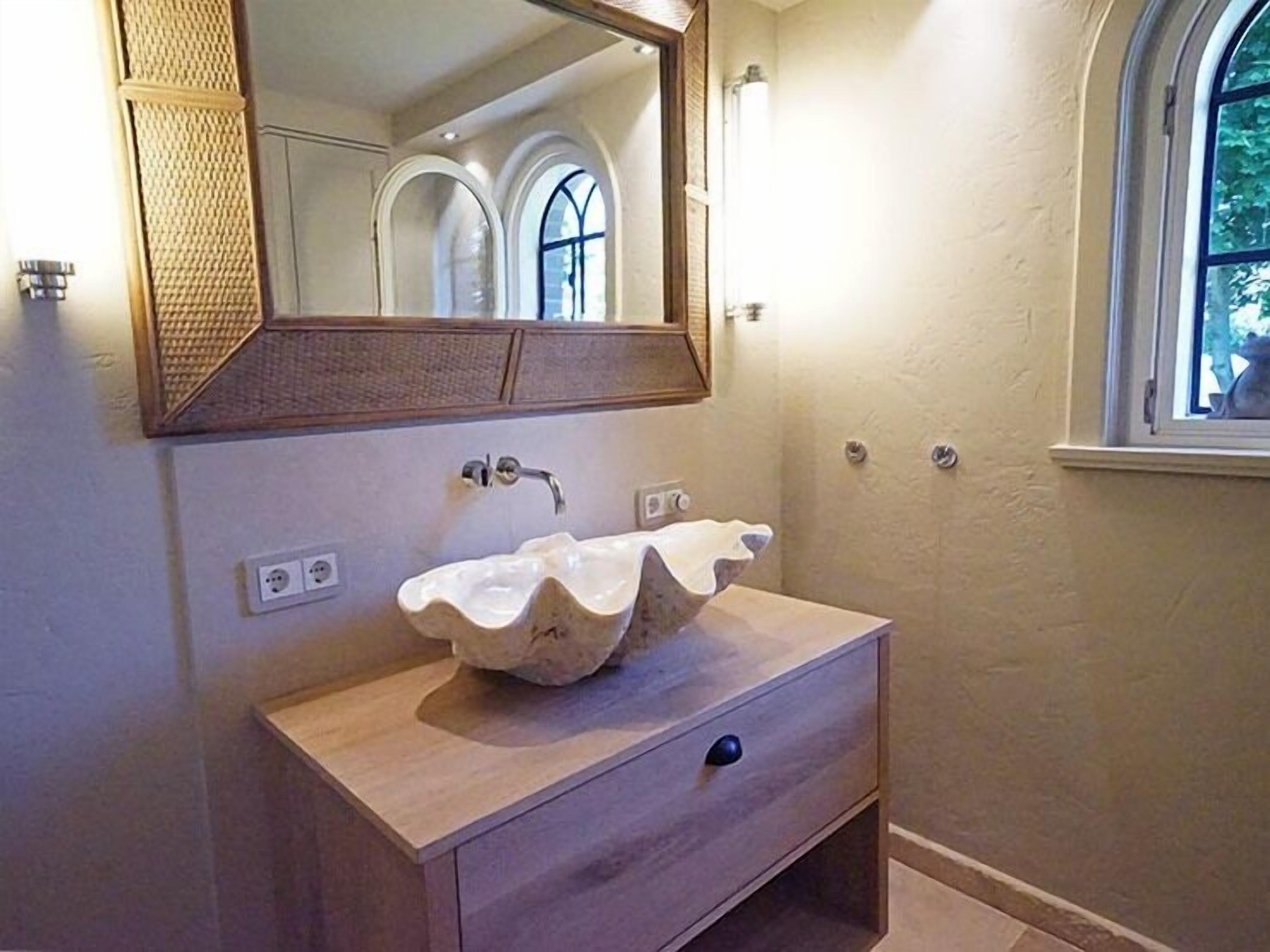 Un baño con lavamanos independiente, un espejo y una ventana.