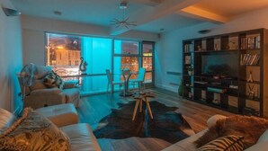 A modern living room with a sofa, a coffee table, and a bookshelf. - Live in Leeds Millenium Square Apartment (Leeds)