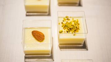 Four square glass dessert dishes with a creamy white filling, one topped with an almond and another with pistachios.