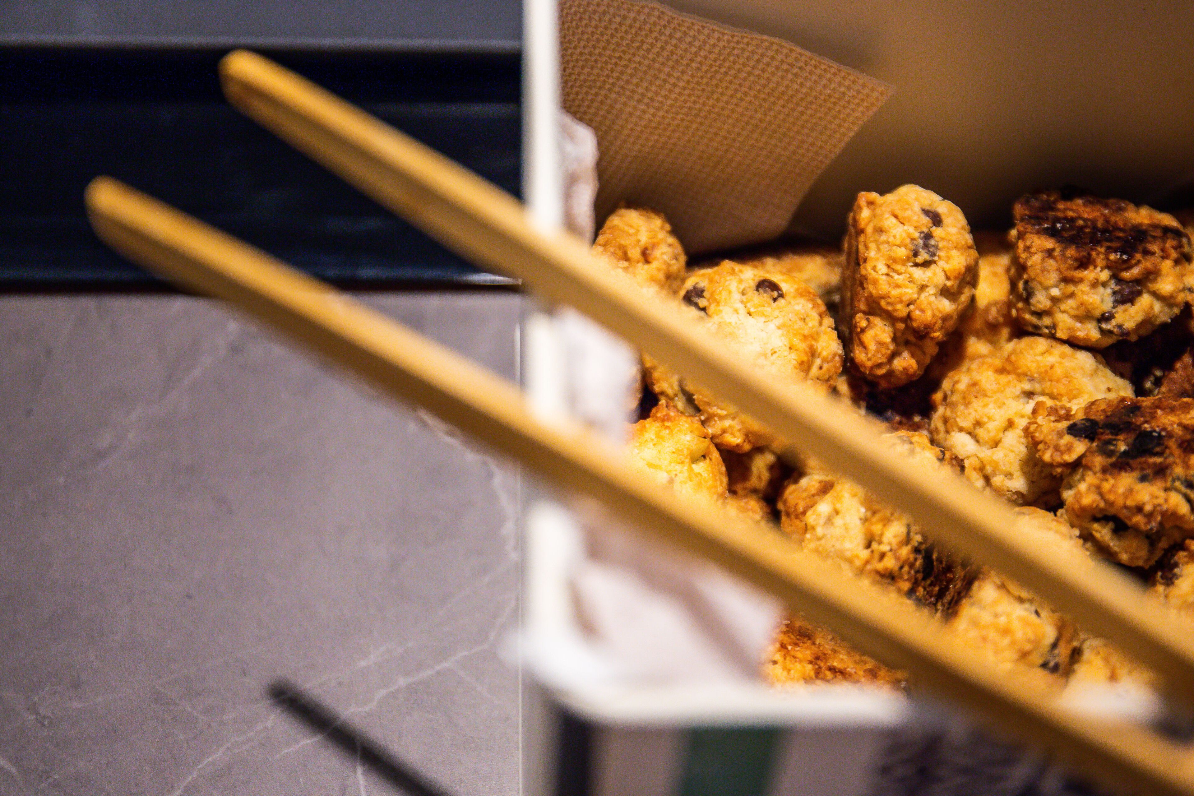 A container of fried food items, possibly chicken or fish, with chopsticks resting on top.