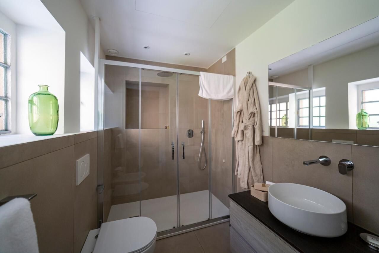 Une salle de bain moderne avec une douche à parois de verre, un lavabo blanc et un grand miroir.