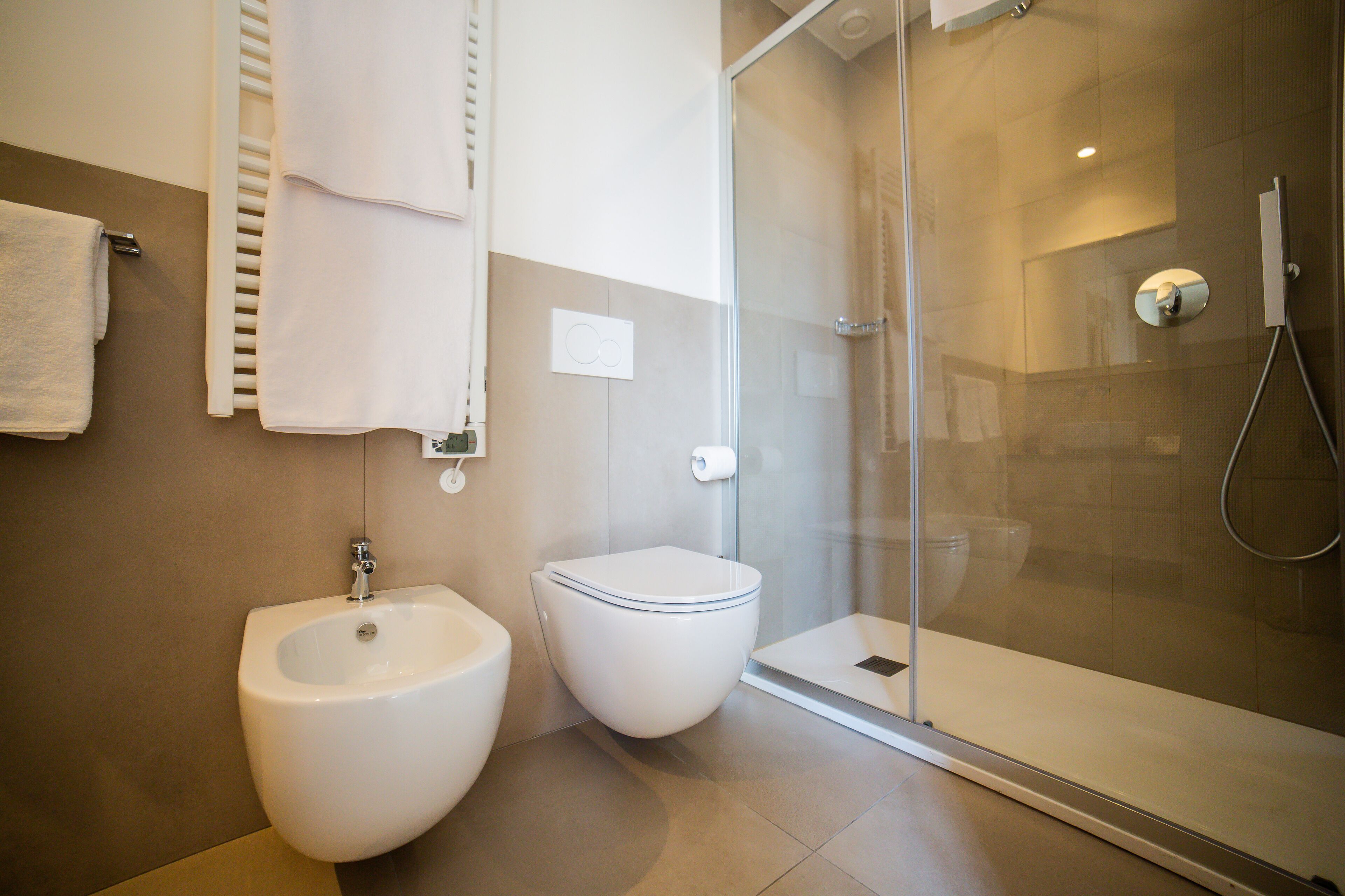 Un bagno moderno con bidet, water e doccia vetrata.