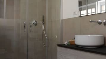 A modern bathroom with a glass-enclosed shower, a white sink, and a large mirror.