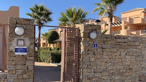Un cancello in pietra con una targa blu e un cartello con un numero.