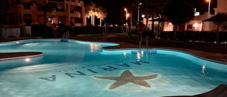 Una piscina al aire libre, sillones reclinables de piscina