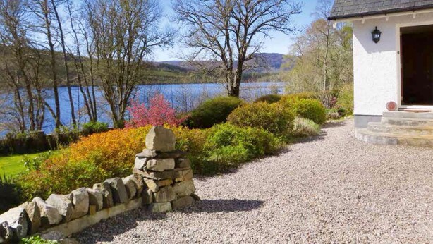 A house with a stone wall and gravel path leading to a wooden door. - Lochview Guesthouse (Strathpeffer)