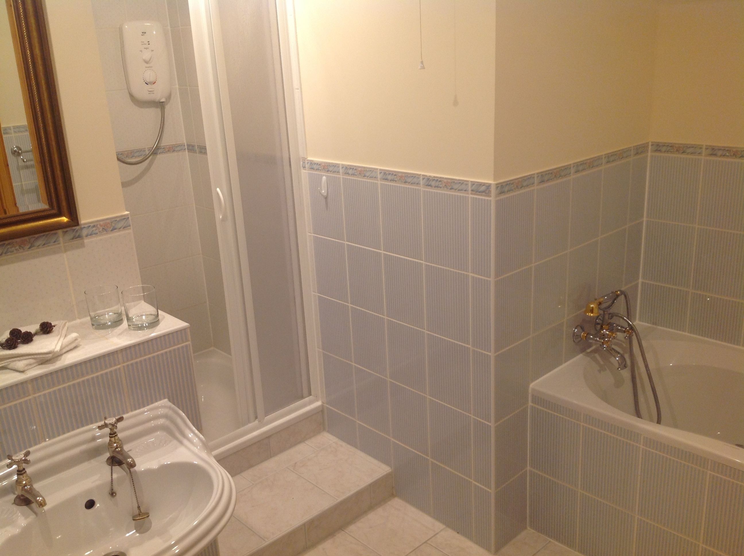 Un baño con lavamanos, dos grifos, un espejo, cabina de ducha y bañera.