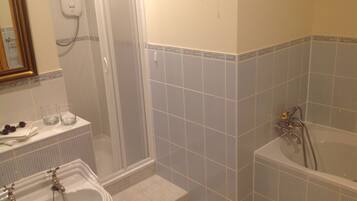 Un baño con lavamanos, dos grifos, un espejo, cabina de ducha y bañera.